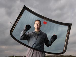 Car mechanic holding rear windscreen with suction pads